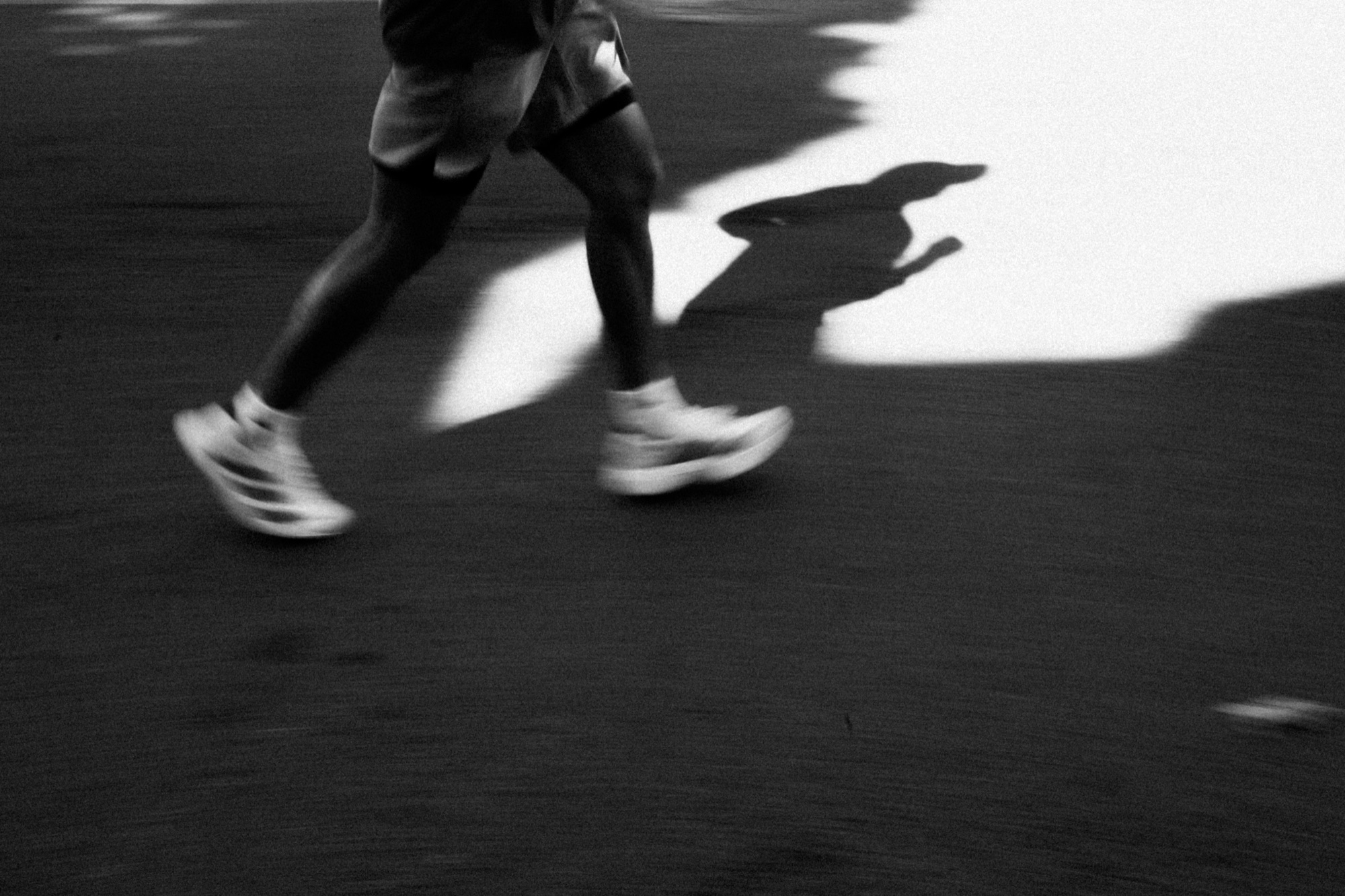 Close-up of running legs and shoes, motion-blurred on dark pavement.